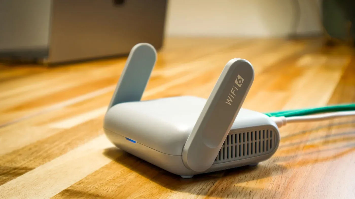 Liten vit wifi-router med två antenner på en träskiva