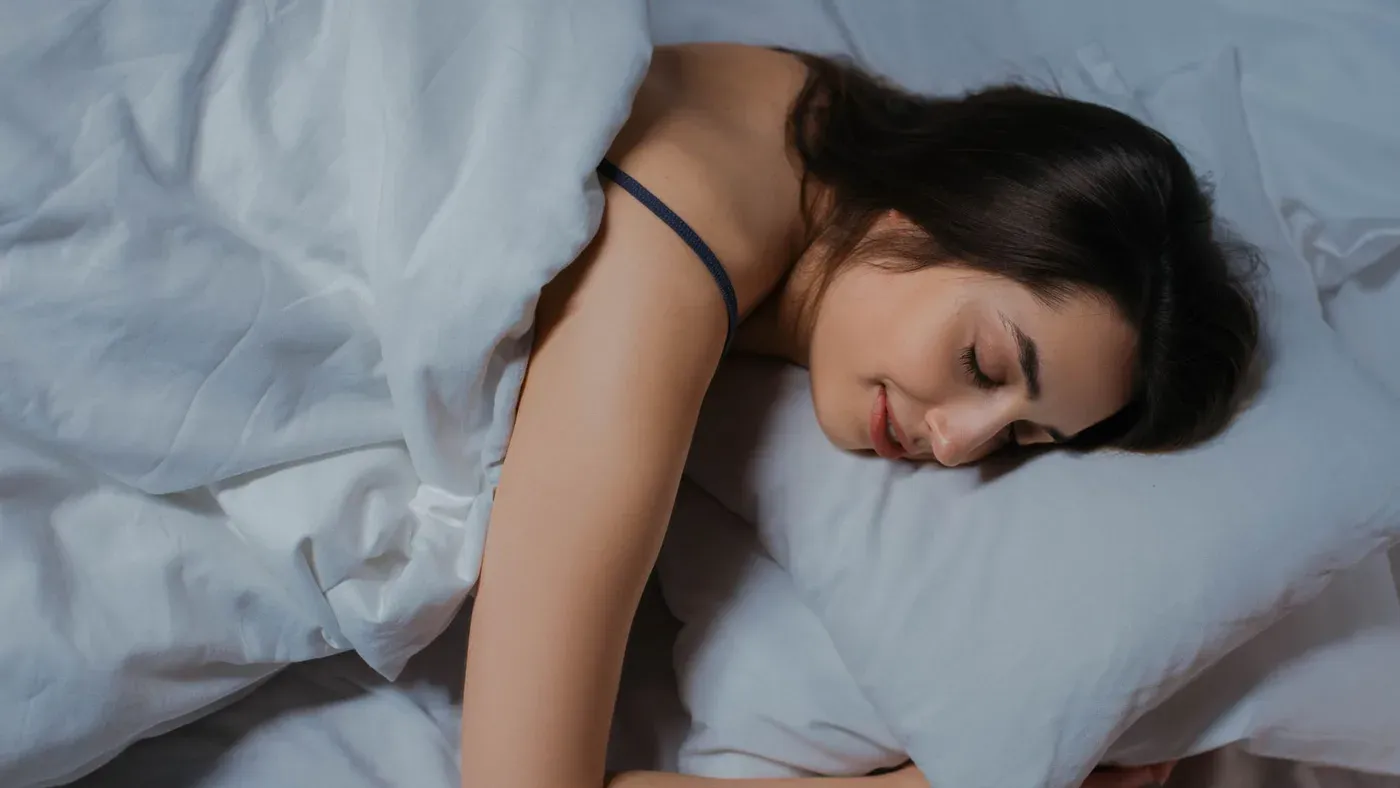 Person som sover i en säng med vita sängkläder