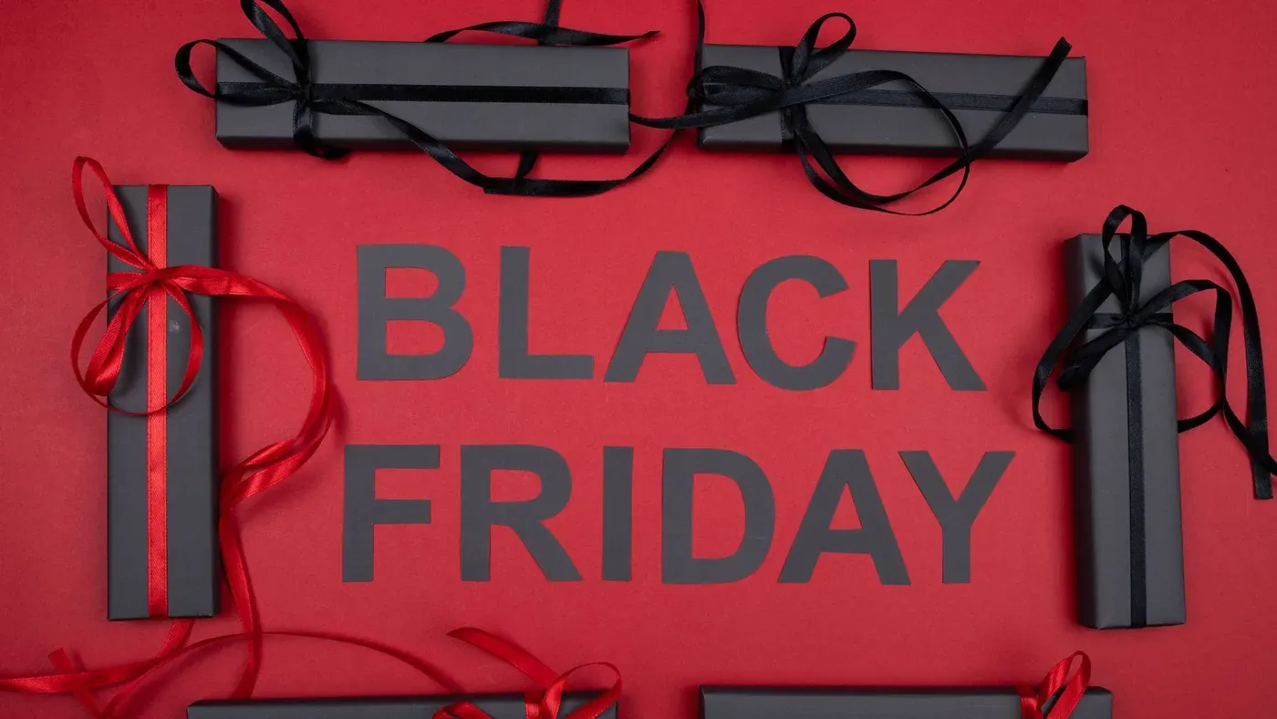 Texten BLACK FRIDAY i svarta bokstäver på röd bakgrund, omgiven av svarta presentpaket med band