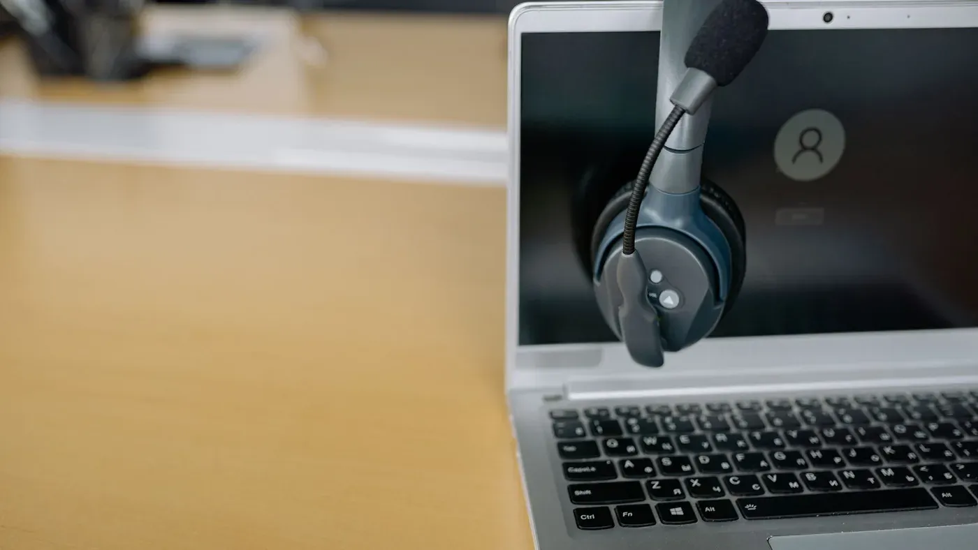 Headset som hänger på en bärbar dator på ett skrivbord